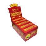 En pakke cigaretter præsenteres med et slankt, rektangulært design. Farven er primært sort med detaljer i hvidt og rødt. På forsiden er der et grafisk motiv, der inkluderer tekst og symboler. Mønsteret er enkelt, men iøjnefaldende, med en blank overflade, der reflekterer lyset. Etiket inkluderer sundhedsadvarsler i mindre skrift.