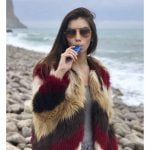 AirVape X vaporizer præsenterer en slank, ergonomisk form med en glat, sort overflade. En digital skærm viser temperaturindstillinger i klare tal. En sølvfarvet knap er placeret på en side, og en lille luftkanal ses på toppen. Enhedens kompakte design gør den let at håndtere, mens de afrundede kanter bidrager til et stilrent udtryk.