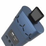 AirVape X vaporizer i en dyb blå farve præsenterer en slank, rektangulær form med afrundede hjørner. Den glatte overflade har en mat tekstur, mens fronten er udstyret med en digital skærm og tre knapper. En lille, sort luftkanal strækker sig opad, og en gennemsigtig glasrør er synligt i toppen, hvilket tilføjer en kontrast til den ensartede farve.