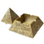 Et askebæger i form af en pyramide præsenterer sig med en glat, reflekterende overflade. Det er fremstillet af metal med en sølvfarvet finish, der giver en moderne og stilren æstetik. Bunden er flad og stabil, mens de skrå sider mødes i en spids top. Askebægeret har en integreret skål med en lille kant til opsamling af aske.