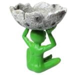 Et sæt af to askebægre med en organisk form. Den grønne farve er lys og ensartet med en glat, blank overflade. Det ene askebæger prydes af en fremtrædende alien-figur, mens det andet har et måne-design. Begge elementer er detaljeret udformet, med tydelige konturer og teksturer, der tilføjer dybde og interesse.