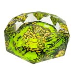Et klart krystalaskebæger med en skarp, geometrisk form præsenterer sig med en glat overflade, der reflekterer lys. Det har en let gul nuance, der minder om citrongul, og kanter med præcise, skarpe linjer. Bunden er bred og stabil, mens området til cigaretter er indsnævret, hvilket giver en elegant, moderne fremtoning.