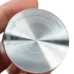En sort, glat leaf-formet genstand med en længde på 59 mm. Overfladen har en let reflekterende finish, der skaber et subtilt skær. Den er opdelt i to sektioner, der mødes ved en skarp kant. Uden synlige mønstre eller tekst, fremstår den minimalistisk med en elegant, strømlinet form, der udstråler enkelhed.