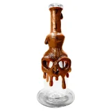 En brun keramikbong med et sort fårhoved som dekoration. Bongen har en glat overflade med en let skinnende finish. Fårhovedet er detaljeret med fremtrædende horn og teksturerede ansigtstræk, der skaber dybde. Der er en gennemsigtig glasindsats, der skaber kontrast til den matte keramik. Bongen har en elegant, buet form med en stabil base.