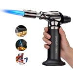 En sølvfarvet gaslighter med en glat, metallic overflade pryder midten af beskrivelsen. Den har en rektangulær form med let afrundede kanter. Forenden rummer en flammeudløser med en sort gummibelægning og en synlig flammejustering. Bagpå er der en gennemsigtig tank, der viser gasniveauet. Lighteren fremstår elegant og moderne med en minimalistisk designstil.