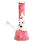 En høj, slank beaker i klart glas med en let pink nuance pryder overfladen. Beakeren har en glat, gennemsigtig tekstur, der fanger lyset og skaber en blød glød. Den har en bred åbning og en let udvidet top, hvilket giver en elegant silhouette. Det enkle design fremhæver den bløde farve og det minimalistiske udtryk.