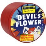 En rund, flad grinder med en diameter på 63 mm. Overfladen er mat sort med en let struktureret tekstur. På toppen pryder et detaljeret, farverigt blomstermotiv i nuancer af rød, gul og grøn, der skaber kontrast til den mørke baggrund. Grinderens kanter er glatte, og den åbnes med en skruefunktion. Det indvendige rum har skarpe tænder til effektiv formaling.