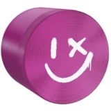 En lilla smiley med en rund form pryder overfladen, hvor ansigtstræk i sort skaber en kontrast. De udtryksfulde øjne og den brede mund formidler glæde. Materialet har en glat, skinnende tekstur, der reflekterer lys. Diameteren måler 63 mm, hvilket giver en iøjnefaldende tilstedeværelse. Det enkle design er præget af en minimalistisk stil.
