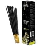 En pakke med incense sticks prydes af en farverig, illustreret emballage. Den dominerende baggrundsfarve er mørkeblå, dekoreret med grønne og gyldne cannabisblade. Teksten er i hvid og gul, skrevet i en letlæselig skrifttype. Øverste del har et mønster af bølger, mens bunden har en simpel, let struktur. Kanten er let afrundet, og emballagen fremstår glat.