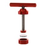 En aluminiumspresse med en rød stempelmekanisme pryder midten. Stempelens overflade er glat og skinnende, mens pressens krop har en børstet finish, der giver en moderne tekstur. Begge dele er designet med præcise kanter og skarpe linjer. Nederst er der en solid base, der sikrer stabilitet under brug.