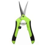 Saksens klinger er buede med en skarp, blank overflade, der reflekterer lys. Håndtaget er ergonomisk designet med en mat, sort finish, der giver et godt greb. Der er en spænde mekanisme, der sikrer lukning. Saksen har en robust konstruktion, der indikerer holdbarhed og funktionalitet, velegnet til præcisionsarbejde.