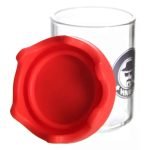 En transparent glasbeholder med en moderne, krystallignende struktur. Beholderens overflade er glat med svage, bølgede linjer, der skaber et spil af lys og refleksioner. Låget er tæt med en præcis pasform, og der er en lille, indadgående kant omkring åbningen. Farven er klart glas, hvilket fremhæver indholdet indeni.