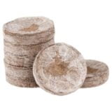 En rund, grønbrun jiffy-pellet med en diameter på 24 mm præsenteres. Pelletens overflade er ru og tekstureret, hvilket indikerer, at den er fremstillet af komprimeret torv. Den er pakket i en flad, cirkulær form uden synlige folder eller defekter. Omkring pelletens kant kan der ses små uregelmæssigheder, der tilføjer til dens naturlige udseende.