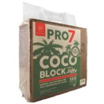 Jiffy Pro7 Coco Block vejer 5 kg og er formet som en kompakt blok. Den har en mørkebrun farve med en ru overflade, der viser små fibermønstre. Blokken er pakket i en plastikfolie, der har en gennemsigtig sektion, hvilket giver indsigt i den strukturerede tekstur. Kanten er skarp, og det samlede udseende er ensartet og solidt.