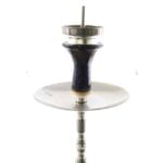 En shisha med en dyb lertragt, der er fuldt glasurbelagt i en dyb blå farve. Tragten har en glat, skinnende overflade, der reflekterer lyset. Den runde form er præcist udformet, og kanten er let buet. Nederst er tragten forbundet til en slange, der er lavet af metal, med en mat finish.