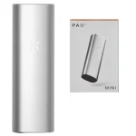 PAX Mini vaporizer præsenterer en slank, kompakt form i en metallisk sølvfarve. Overfladen har en glat, reflekterende tekstur. En lille, rund knap er placeret på forsiden, omgivet af en subtil lysindikator. Ventilationshuller er strategisk placeret i bunden. Det samlede design fremstår minimalistisk og funktionelt, med bløde kanter og en let buet kontur.