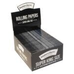 Displayboks med flere pakker "Smokers Choice - Rolling Papers Black Super King Size," sort med hvid tekst, åbnet foroven og afsløre de pæne arrangerede pakker indeni.