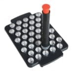 Filling set består af flere dele i sort plast og rustfrit stål. Der er en cylindrisk beholder med en bred åbning og en flad bund, som rummer doseringskapsler. En skovl i samme materiale er placeret ved siden af, med en smal, afrundet spids. Et lille, gennemsigtigt låg, der passer til beholderen, er også synligt, og det hele har en glat overflade.