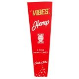 Tre cigaretpapir ruller præsenteret i en lukket, rektangulær pakke. Pakken er lavet af kraftigt papir med en grønlig tone og sorte detaljer. Fronten har et mønster af stiliserede koner og tekst i hvid. Hver rulle er lang og smal, med en glat, hvid overflade. Pakken er lukket med en klap, der sikrer indholdet.