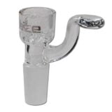 En gennemsigtig glasskål med en glat, skinnende overflade pryder midten. Kålen har en let buet form, der giver den en elegant silhuet. Den er indrammet af en sort metalbase med en robust struktur, der stabiliserer skålen. Skålen har en subtil blålig nuance, hvilket fremhæver dens klare glas. Det samlede design udstråler en minimalistisk æstetik.