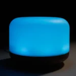 Aroma diffuseren har en oval form med en glat, trælignende overflade i en varm, lys brun nuance. Øverst er der en rund åbning til vandbeholderen, der er beskyttet af en klar plastdæksel. En svag, blød lysindikation kan ses fra bunden. En USB-port er placeret på siden, hvilket giver mulighed for tilslutning. Diffuserens design er minimalistisk og elegant.