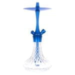 En cylindrisk lampe med en glat, blå metaloverflade pryder toppen, mens en hvid, gennemsigtig glasdel spreder lyset. Lampens base er rund og stabil, fremhævet af en let tekstur. En slank, sort ledning strækker sig fra lampens base, og en enkelt, sort kontakt er placeret på ledningen. Designet er enkelt og moderne med fokus på funktionalitet.