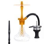 En gylden lampe i en klassisk, orientalsk stil pryder overfladen. Lampen har en buet, skulpturel form med detaljeret mønstring, der skaber et indviklet lys- og skygge-spil. Den er fremstillet af metal med en blank overflade, der reflekterer lys. En fin, dekorativ krone afslutter toppen, mens en lampefod i samme stil giver stabilitet.