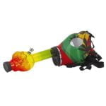 En gasmaske med et farverigt rasta-design pryder overfladen med grønne, gule og røde striber. Masken har en mat tekstur og tydelige, runde øjenlinser, der reflekterer lys. Mundstykket er sort og har en glat finish. Det samlede udtryk er præget af et urbant, kunstnerisk element, der kombinerer funktionalitet med visuel appel.