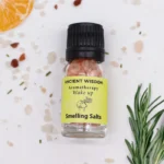 En rund, hvid skål i keramik prydes af en naturlig, uregelmæssig form og en glat, blank overflade. Indholdet består af grovkornet, hvidt salt, der glitrer svagt i lyset. Skålen er placeret på en simpel, lys overflade, der fremhæver den rustikke æstetik. Ingen synlige mærker eller dekorationer pryder skålen, hvilket giver et minimalistisk indtryk.