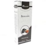 En pakke incense med en mørkebrun, glat overflade prydet med gyldne detaljer. Forsiden bærer teksten "Aromatica Premium Incense" i en elegant skrifttype. Baggrunden er prydet med et subtilt mønster, der giver dybde. Øverste del af pakken har et let skinnende finish, mens bunden er mat. Farverne er varme og indbydende, primært i nuancer af brun og guld.