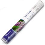 En pakke med aromatiske røgelsespinde præsenterer en dyb lilla farve, der dominerer emballagen. Mønsteret er enkelt og elegant, med en guldfarvet tekst, der angiver produktnavnet. Røgelsespindene er synlige gennem en gennemsigtig åbning, hvilket fremhæver deres naturlige brunlige farve og tekstur. Foran pakken er der en skålen med lavendelblomster, der tilføjer en naturlig detalje.