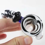 En skål i sort glas præsenterer en elegant svungen form med en dyb bund og brede kanter. Overfladen har en glat tekstur, der reflekterer lys, hvilket skaber en subtil glans. Mønstret i glasset viser en sort virvlet effekt, der tilføjer dybde og karakter. Skålen er placeret på en neutral overflade, der fremhæver dens form.