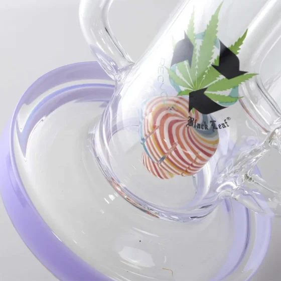 En høj, slank bong i sort glas prydet med detaljer i lilla. Den har en buet form og en bred, stabil fod. Overfladen er glat, mens den lilla farve skaber en kontrast ved slangen og toppen. En perkolator ses indeni, hvilket tilføjer et komplekst design. Bongen har en indbygget skål og en tæt passform for sikker anvendelse.