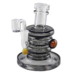 En klar, cylindrisk glasbanger med en højde på 16 cm præsenterer sig med en glat overflade og en skinnende, transparent struktur. Den har en bred, flad bund og en indadgående hals, der afsluttes med en skarp kant. Glasset er tykt og robust, mens den øverste del har en let buet form, der skaber et elegant udtryk.