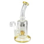 En gul dab rig i glas med en slank, kurvet form. Den måler 24 cm i højden og har en afrundet bund, der giver stabilitet. Røret er klart med en glat overflade, og det har detaljer som en integreret perkolator med små huller. Der er en indbygget skål til koncentrater, og riggen prydes af subtile mønstre.