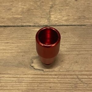 Et aluminiumshoved i rød farve, præcist udformet uden gevind. Overfladen er glat med en let metallisk glans, der reflekterer lys. Formen er cylindrisk med en flad top, og kanten har en let afrunding. Den samlede struktur er robust og kompakt, hvilket giver et minimalistisk udtryk. Ingen synlige insignier eller teksturer pryder overfladen.