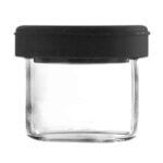 En lille beholder med en rund form, fremstillet af transparent plast, præsenteres. Den har en silikone-top i en klar farve, der giver en blød tekstur. Beholderen rummer 5 ml og har en glat overflade uden mønstre. Der er en let skruefunktion i toppen, der muliggør lukning. Farven er klar, hvilket giver indholdet indblik.