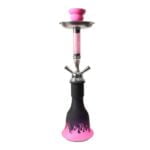 En pink havevander med to slanger strækker sig fra en rund, hvid bundplade. Slangerne er glatte og fleksible, med en lysere pink nuance og matcher vanderen perfekt. Håndtaget er robust og har en ergonomisk form, mens der er små drænhuller i bunden for vandafledning. Den samlede stil er moderne og funktionel.