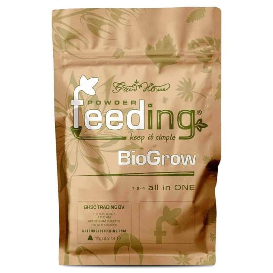En grøn, firkantet beholder med en skruehætte præsenterer en 1 kg pakke med et grønt og hvidt design. Fronten bærer teksten "BioGrow" i stor, tydelig skrifttype, omgivet af grønne blade og en grafisk repræsentation af et planteelement. Beholderen har en mat overflade, mens hætten har en glat, skinnende finish. Mærkets logo er synligt i øverste del.