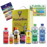 En starterbox til planter præsenterer en rektangulær papkasse med en naturfarvet overflade. Kassen indeholder flere runde potter i sort plast, fyldt med mørk, fugtig pottemuld. Enkle grønne frøposer er placeret ved siden af potterne, med tydelig tekst og illustrationer. Kassen har en åben top, der afslører indholdet og giver nem adgang til materialerne.