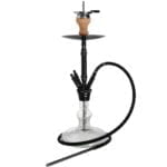 En cylinderformet pendel lampe hænger fra loftet, fremstillet af metallisk materiale med en mat sort finish. Lampens overflade har en let struktureret tekstur, der reflekterer lyset svagt. Den har en diameter på 58 cm og en integreret LED-lyskilde, der udsender et varmt, indbydende lys. Kablet, der holder lampen, er slankt og diskret.