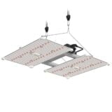 En sort LED-lampe med en flad, rektangulær form og en mat overflade. Den har en tydelig blæsergitterstruktur på den ene side og flere knapper til justering, der er placeret på fronten. Kablet er sort og strakt fra bunden. Den samlede æstetik er minimalistisk med en funktionel opbygning, der signalerer moderne belysningsdesign.