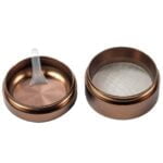 En rund, bronze farvet skive med en diameter på 60 mm præsenterer sig med en glat overflade, der reflekterer lys svagt. Skivens kant er let buet, og den har en metallisk glans. I midten er der en tydelig indgravering, som tilføjer tekstur og dybde. Baggrunden er neutral, hvilket fremhæver skivens detaljer.