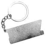 En nøglekæde i råmetal præsenterer sig med en mat, grå overflade. Den har en simpel, cylindrisk form med let buede kanter. Kæden er udstyret med en solid ring, der forbinder en lille, rund plade. Pladen bærer en indgraveret tekst, der står i store, sans-serif bogstaver. Det rå metal giver et industrielt udtryk med en let ru tekstur.