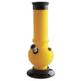 En gul akryl bong med en højde på 21 cm har en glat, gennemsigtig overflade. Den er formet med en buet krop, der smalner ind mod toppen. Bunden er stabil og bred, mens en lille, rund skål er placeret på siden, der fungerer som en tilføjelse til røgkanalen. Det gule materiale giver en livlig og lysende effekt.