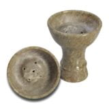 En shisha bowl i grå soapstone præsenterer sig med en glat overflade og en domformet struktur. Diameteren måler 80 mm, og den har en dybde, der muliggør opbevaring af tobaksblanding. Mønsteret på skålen er subtilt, med lette nuancer og skygger, der fremhæver materialets naturlige tekstur og porøsitet.