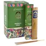 Masala chai røgelsespinde præsenteres i en elegant, sort emballage med gyldne detaljer og et farverigt mønster. Røgelsespindene er lange og slanke, i en dyb brun farve, med en glat overflade. På emballagen er der indgraveret tekst og symboler, der fremhæver produktets indhold, samt information om oprindelse og anvendelse. Designet er både traditionelt og stilfuldt.