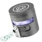 En grå, automatisk krydderigrinder med en slank, cylindrisk form. Overfladen er lavet af rustfrit stål, hvilket giver en glat og skinnende tekstur. Den øverste del har en sort, gummibelagt knap til aktivering. På fronten er der et klart vindue, der afslører indholdet. Bunden er forsynet med en skridsikker gummiring for stabilitet.