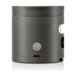 En grå automatisk grinder præsenterer en strømlinet og moderne form. Den har en glat overflade med en mat finish, der giver et stilrent udtryk. Knappen til betjening er placeret på toppen, og der er en transparent beholder til opbevaring af malet materiale. Grinderens krop har en cylindrisk form, der afsluttes med en let buet kant.