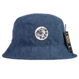 En navy bucket hat pryder sig med en ensartet, dyb blå farve. Materialet fremstår som en blød, men holdbar tekstil med en let struktur. På forsiden er der en broderet detalje, der tilføjer dimension og kontrast. Skyggen har en bred form, der giver en afslappet silhuet, mens kanten er let bøjet opad.